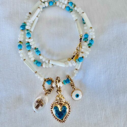 collier NOMAD blanc et turquoise avec charms coeur sacré pailleté bleu turquoise, oeil protecteur et croix sur perle en nacre