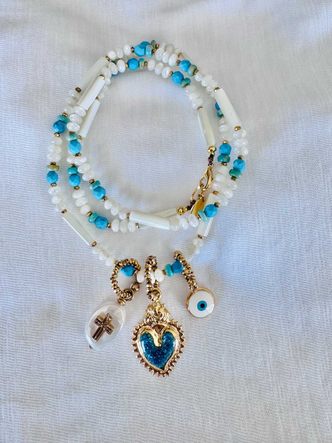 NOMAD coeur turquoise blanc - Mademoiselle Oups collier NOMAD blanc et turquoise avec charms coeur sacré pailleté bleu turquoise, oeil protecteur et croix sur perle en nacre