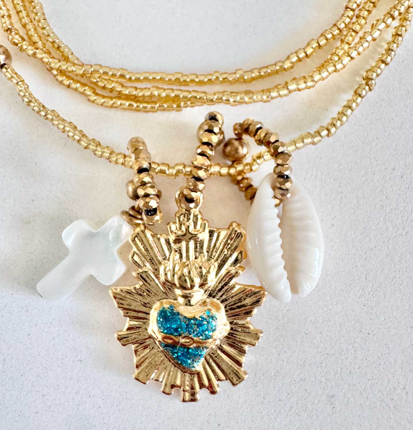 ICON-01-collier-sacre-coeur-turquoise-details Détails du collier ICON 01 Mademoiselle Oups, collier doré avec Sacré-Cœur turquoise, croix en nacre et coquillage cauri