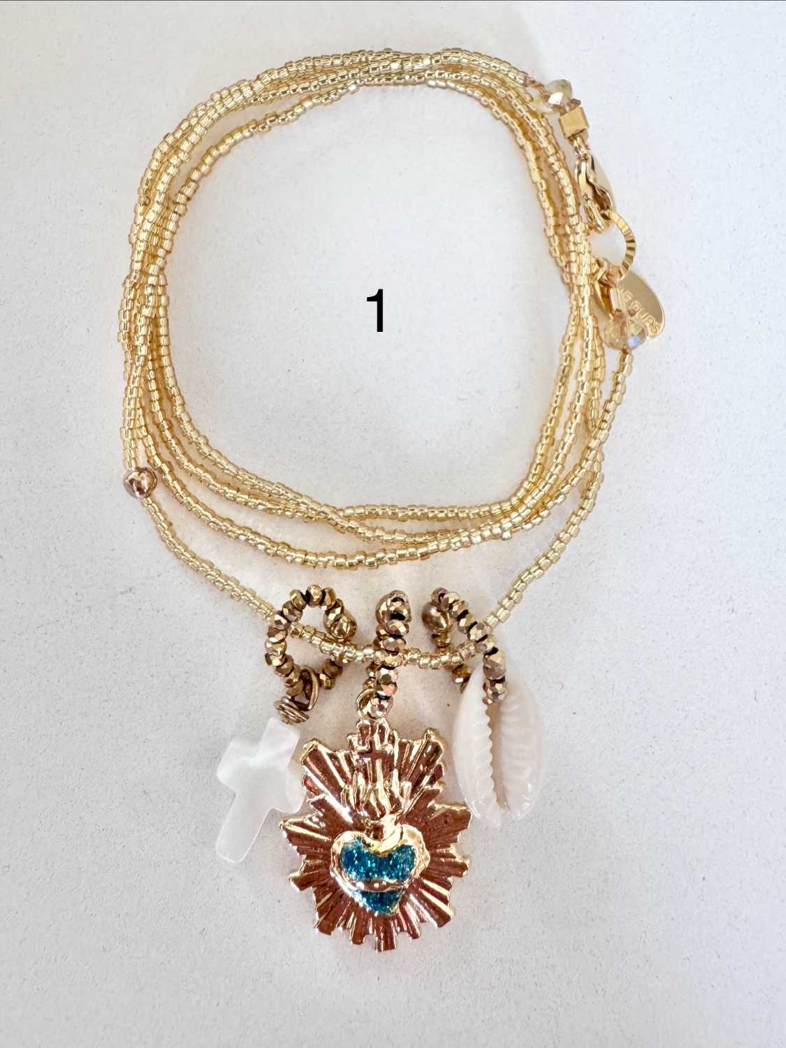 ICON-01-collier-sacre-coeur-turquoise Collier ICON 01 Mademoiselle Oups, collier doré avec Sacré-Cœur turquoise, croix en nacre et coquillage cauri
