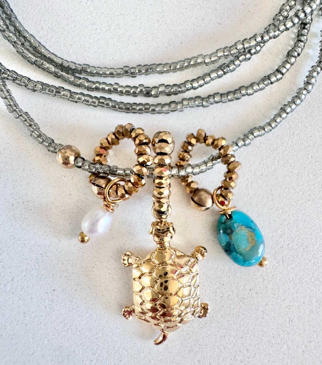 ICON-10-collier-tortue-turquoise-details Détails du collier ICON 10 Mademoiselle Oups, collier gris avec tortue dorée, pierre turquoise et perle de culture