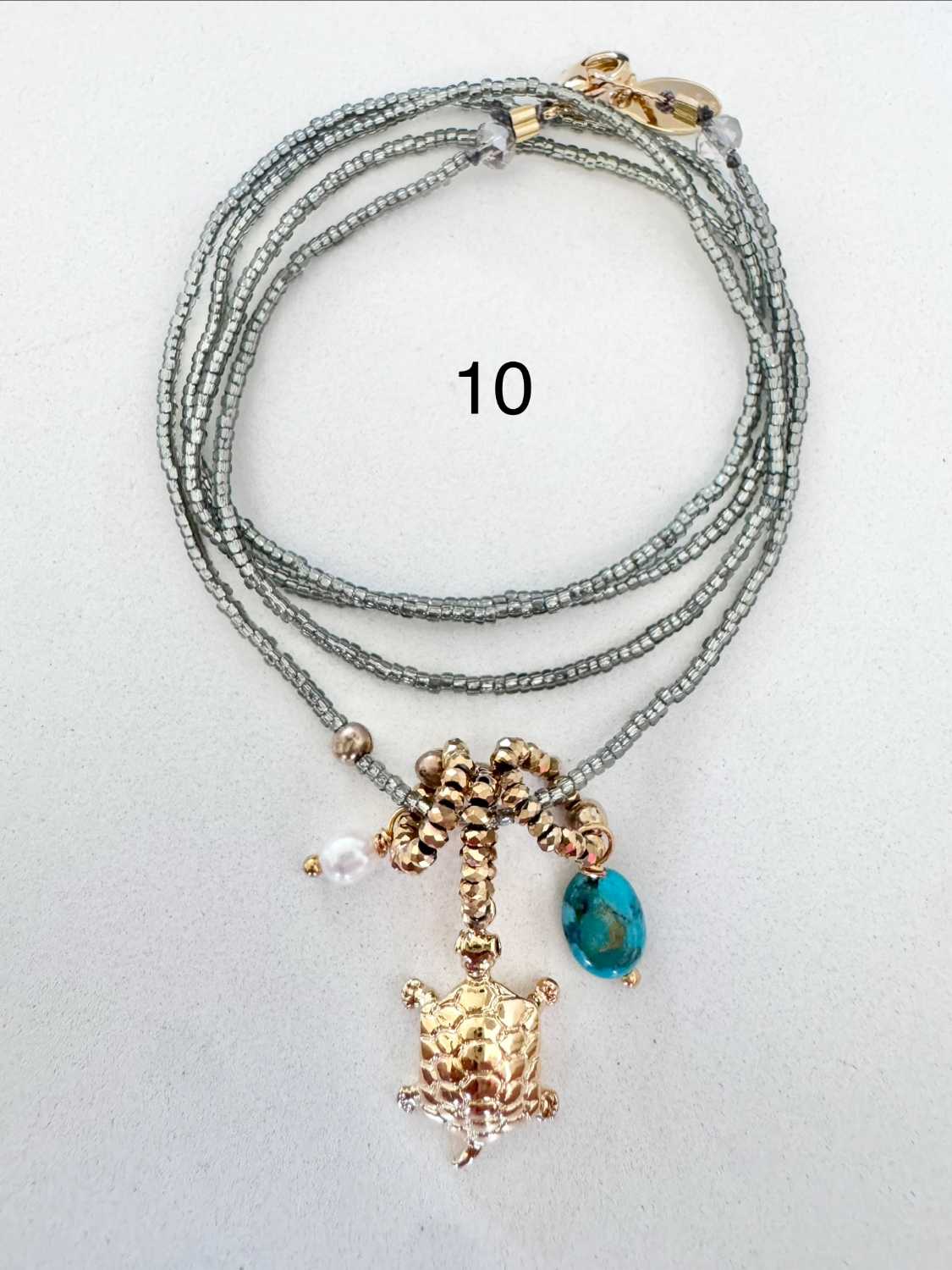 ICON-10-collier-tortue-turquoise Collier ICON 10 Mademoiselle Oups, collier gris avec tortue dorée, pierre turquoise et perle de culture