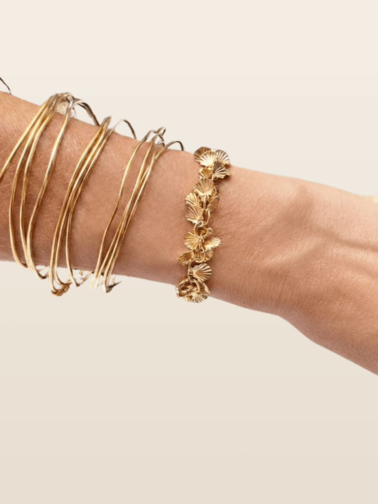 Bracelet Calypso doré à l'or fin 24K, est composé de petits coquillages mobiles, sur poignet, fabrication française, dessiné par Mademoiselle Oups.