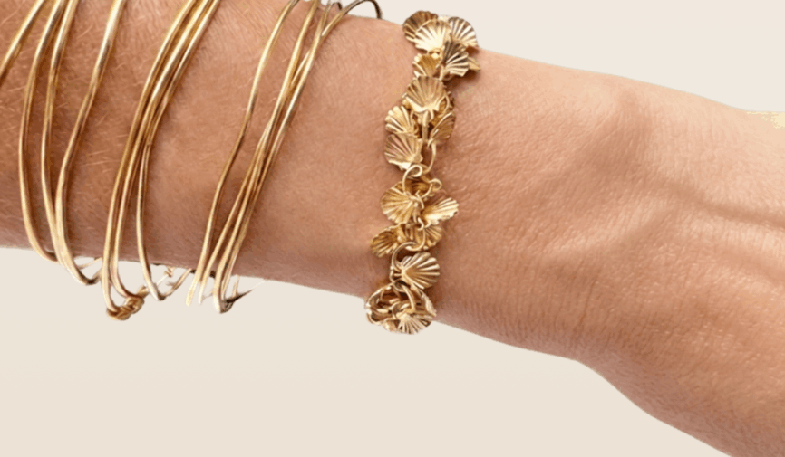 Bracelet Calypso doré à l'or fin 24K, est composé de petits coquillages mobiles, sur poignet, fabrication française, dessiné par Mademoiselle Oups.