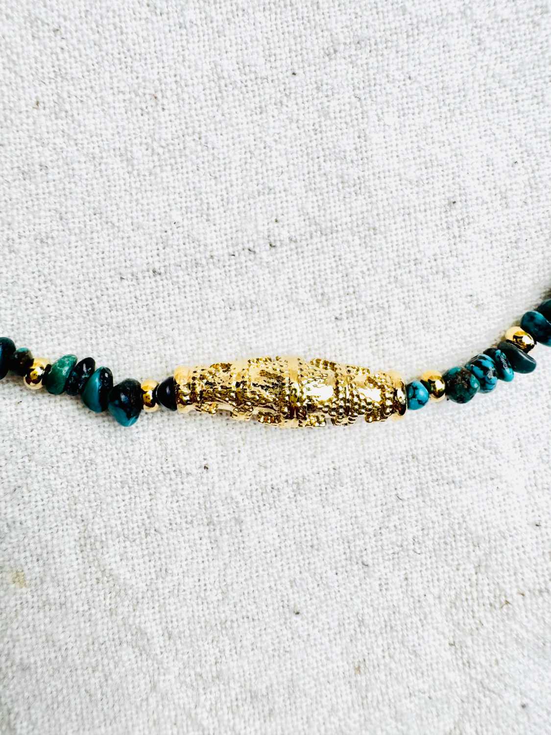 INDIAN-SUMMER-collier-apache-detail-perle-talisman-doree-gravee Collier APACHE en turquoise du Nevada avec grande perle talisman dorée travaillée zoom perle – création Mademoiselle Oups