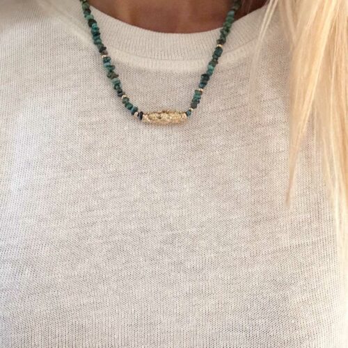 Collier APACHE en turquoise du Nevada avec grande perle talisman dorée travaillée porté sur top blanc – création Mademoiselle Oups