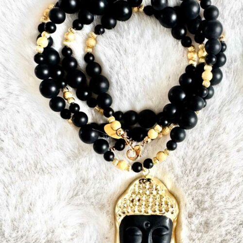 Sautoir NOX en perles d’onyx noir mat de différentes tailles, perles dorées et pendentif Bouddha noir et or, présenté sur fond clair.